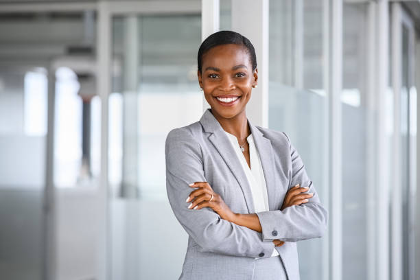 Portrait of mid adult successful black mature woman looking at camera with arms crossed. Smiling african american business woman standing in new office with copy space. Portrait of mature beautiful and confident businesswoman with big smile on her face.